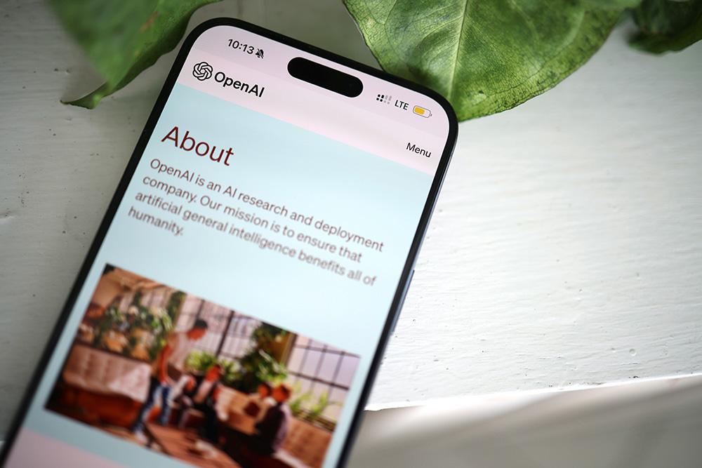 Bild på mobiltelefon och Open AI på skärmen